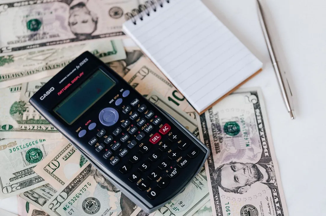 Jar of coins and a calculator on a kitchen table